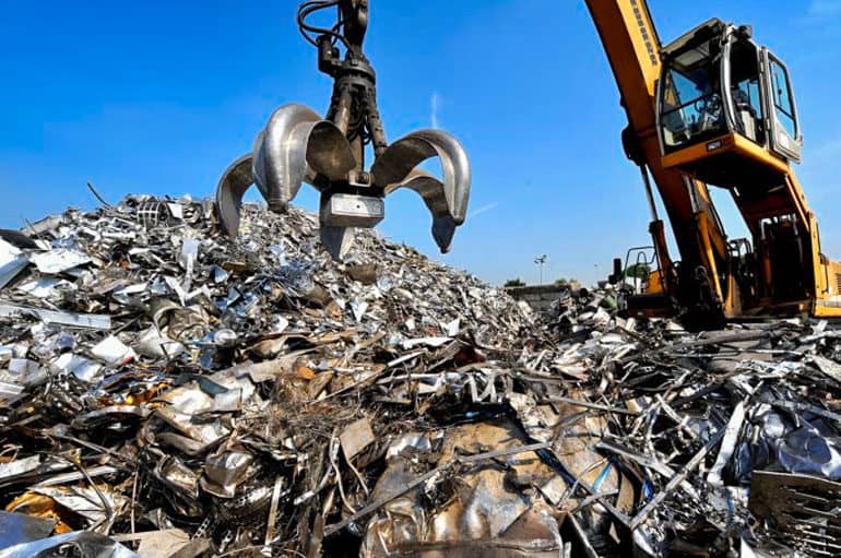 Scrap metal pile with heavy machinery lifting metals, eco-friendly recycling services in Hamilton.